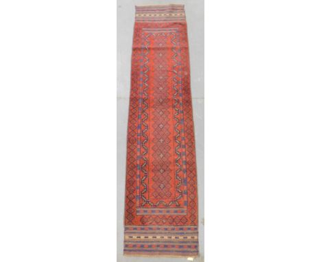 A Pakistan red bound runner, decorated with floral geometric motifs, within repeating foliate and floral borders, 272cm x 60c