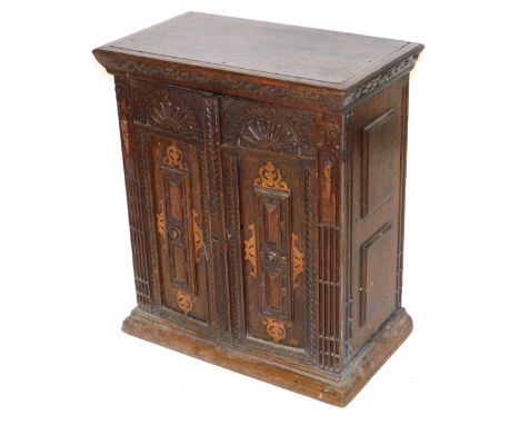 An 18thC Continental oak parquetry cupboard, with two carved panelled doors, enclosing a single shelf, raised on a plinth bas