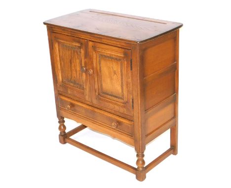 An Ercol elm cupboard, with two doors over one long frieze drawer, raised on turned legs united by a box stretcher, 88cm high