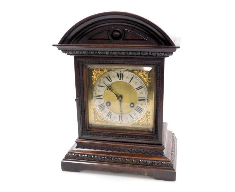 A late 19thC German oak cased mantel clock, square brass dial with foliate spandrels, silvered chapter ring bearing Roman num