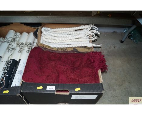 A box containing various cushion covers; curtain tie backs; red throws etc