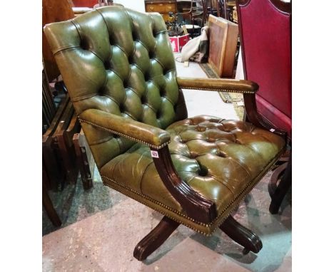 An early 20th century mahogany office swivel open armchair, with button back green leather upholstery.  B7
