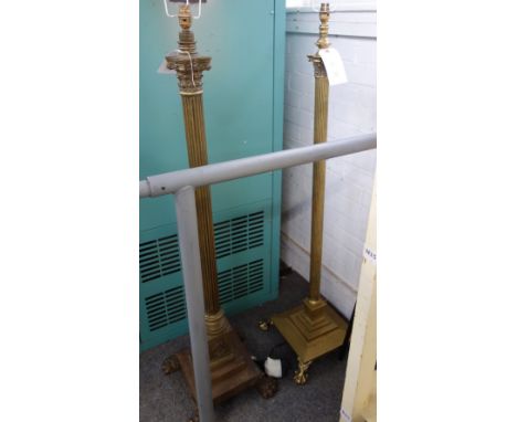 A Victorian brass standard lamp of Corinthian column form, on a stepped square base and four lion paw feet, with a cream silk
