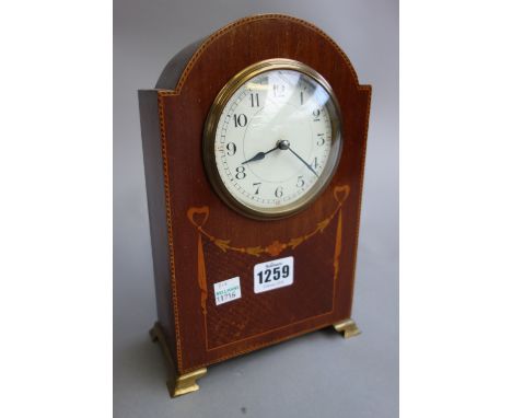 An Edwardian mahogany and inlaid mantel clock with domed top and brass bracket feet with a French single train movement, 24cm