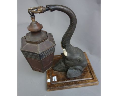 A painted metal wall lantern cast as an elephant head, early 20th century, the outstretched trunk holding a hexagonal lantern