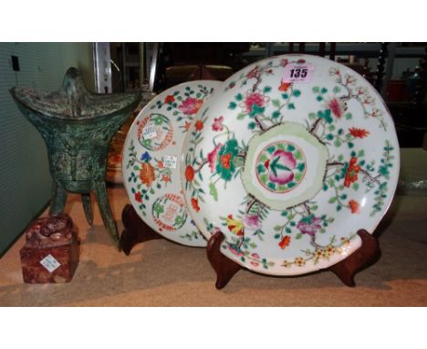 Two Chinese famille-rose plates, 20th century, painted with flowers and fruit, each approx. 22cm. diameter, wood stands; also