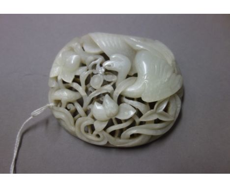 A Chinese white jade pierced plaque, carved with two birds amongst lotus, 10cm. wide.  Illustrated