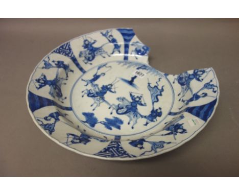 A large Chinese blue and white dish, Kangxi, painted in the centre with two warriors on horseback with attendants, beneath a 