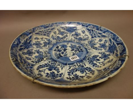 A Chinese blue and white dish, Kangxi, painted with a central panel of flowers inside barbed edged radiating flower panels, (