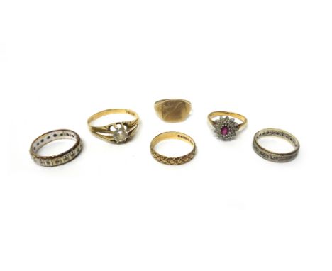 A 9ct gold, ruby and diamond set oval cluster ring, a 9ct gold wedding ring with textured decoration, a colourless gem set et