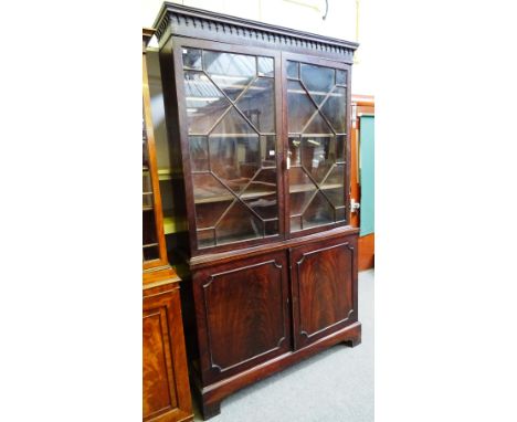 A George III mahogany bookcase cabinet, the pair of glazed doors over pair of cupboards, on bracket feet, 128cm wide x 225cm 