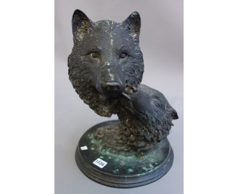 A modern patinated bronze depicting two wolf heads, indistinctly signed '....Bowe Dec 97', on an integral circular stepped ba