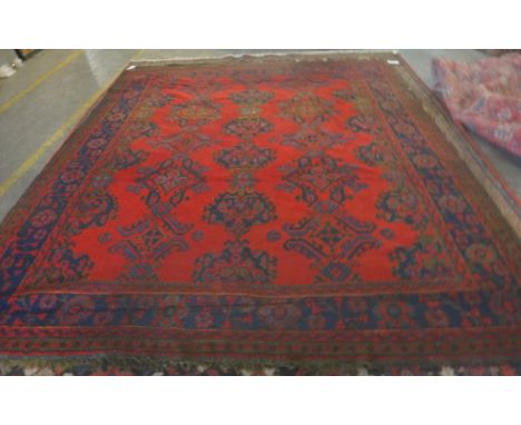 A Turkey carpet, the red field with three columns of stylised medallions, an indigo rosette and leaf spray border, 350cm x 30