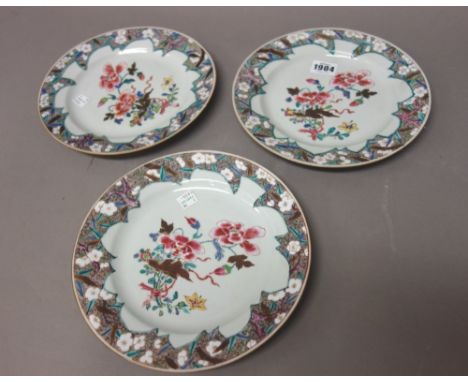 Three Chinese famille-rose plates, early Qianlong, each painted with a central group of flowers inside a brown whorl border p
