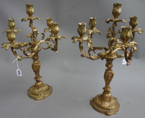 A pair of Rococo style gilt bronze five branch candelabra, each foliate cast over a shaped circular foot, 50cm high, (2).