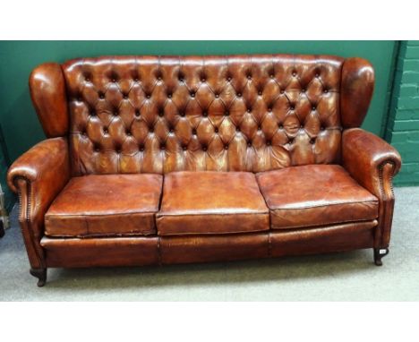 An early 20th century tan leather button upholstered wingback sofa, on squat cabriole supports, 188cm wide x 95cm high.