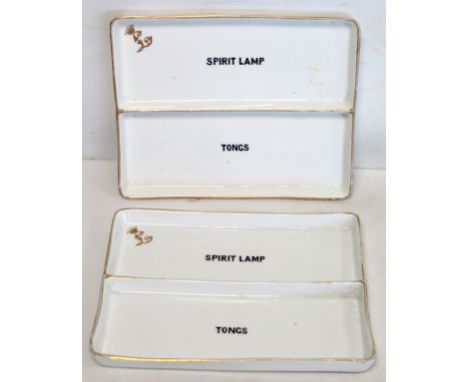 Two white porcelain rectangular trays with central partition, one side inscribed "spirit lamp", the other "tongs", each with 