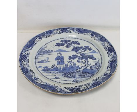 Large 18th century Chinese blue and white circular charger, the central panel depicting a man standing with crossed arms on a