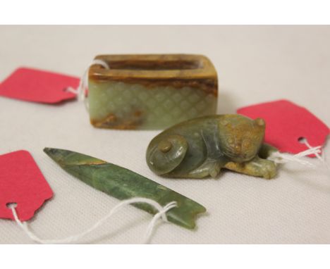 Three Chinese archaic and archaised jade figures to include a repose cat figure, a rectangular toggle of mottled jade and an 