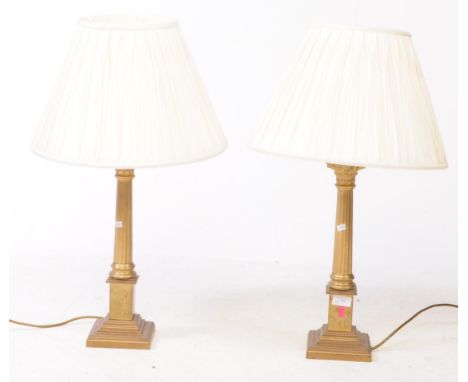 A pair of early 20th century brass neo-classical table lamp lights. Each with square bases and doric column stems with shades