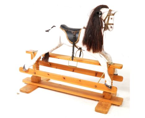 A contemporary painted wooden rocking horse. The dapple grey rocking horse with reigns and saddle. Raised over a pine glider 