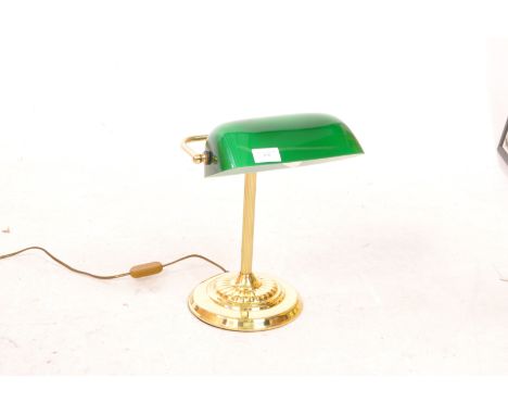 A mid 20th Century vintage bankers table top desk lamp light. Having green glass lightshade supported by brass arm raised on 