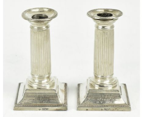 A pair of Edwardian hallmarked silver dwarf candlesticks, with fluted columns and swept bases, Sheffield 1903, height 147cm.&