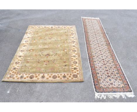 A Persian wool runner, decorated with an all over floral design against a cream ground, 358 x 78cm, with a green ground flora