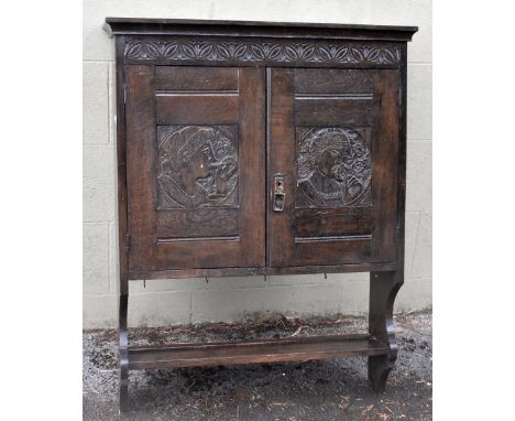 A late 19th century carved oak hanging cupboard with carved floral detail to the top above two carved and panelled doors, dep