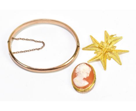 A yellow metal hinged snap bangle, internal width 59mm, approx 6.8g, and filigree decorated cross pendant, 4.9g, and a cameo 