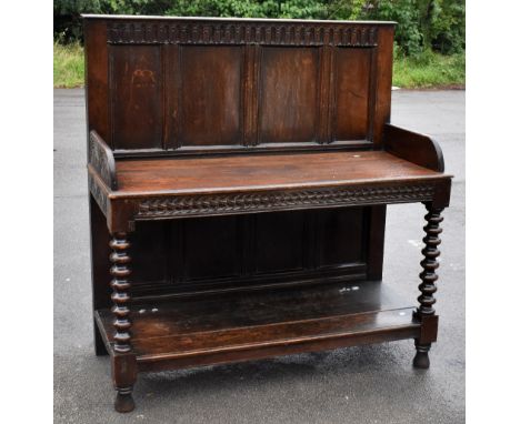 An 18th century and later oak converted buffet with carved and panelled back, with single shelf and carved sides on turned ba