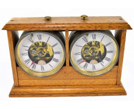 An early 20th century oak cased chess clock, with a pair of circular time pieces, each with replacement card dials, stamped '