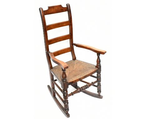 An early 20th century oak and rush seated ladder back rocking chair, height 105cm, depth 63cm, width 60cm.