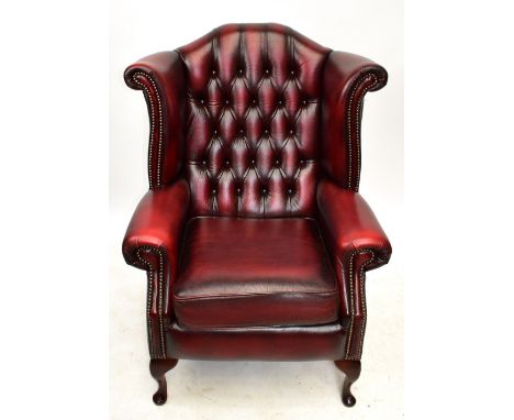A modern wing back armchair with button back and red leather upholstery, height 108cm.