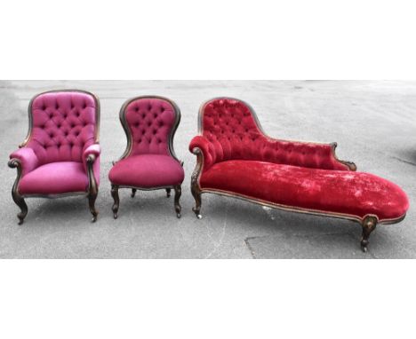 A Victorian carved walnut framed chaise longue, upholstered with maroon button back material on scrolling supports, length 16