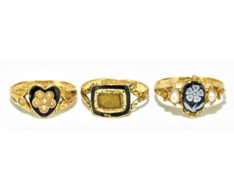 Two 18ct yellow gold black enamel decorated mourning rings, sizes M and L, and a yellow metal mourning ring with central carv