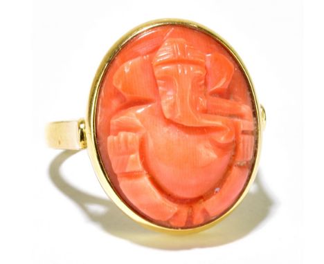 A yellow metal and carved coral ring, the platform detailed as Ganesh, size Q, ring head measures approx 20 x 14mmapprox 9g.