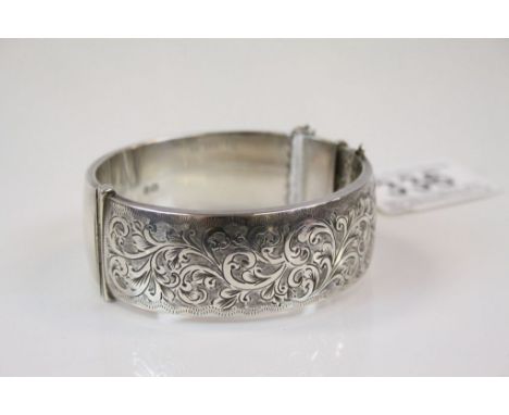 Silver hinged bangle with engraved foliate scroll decoration to upper half, makers Smith &amp; Pepper, Chester 1962, tongue a