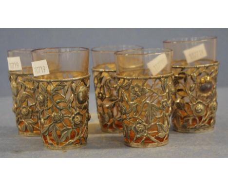 Five vintage Chinese silver cased liqueur glasses each with embossed and pierced blossom decorated casing, enclosing amber gl