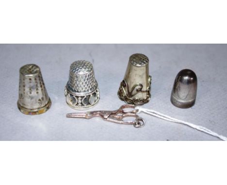 Three various vintage silver thimbles together with a pair of silver stork form scissors, and a silver needle sharpener. Weig