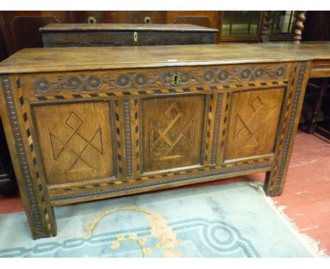 AN ANTIQUE OAK INLAID COFFER, the two plank top with iron pin hinges, leaf and disc frieze decoration and stylized star patte