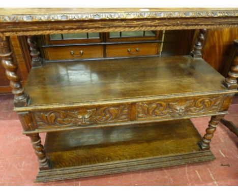 A 20th CENTURY JACOBEAN OAK DUMB WAITER, three shelf with mask carved railback, twist column dividing supports, twin central 