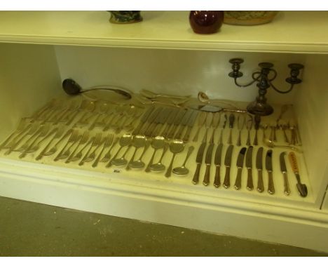 A silver plated eight place cutlery set, a three light candelabra and a large plated ladle 