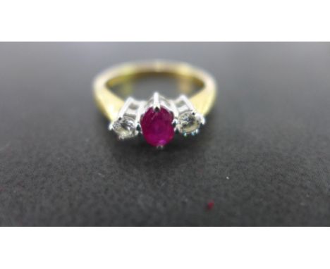 An 18 ct gold ruby and diamond three stone ring, the central oval cut ruby measures approx. 6mm in length - the diamonds each