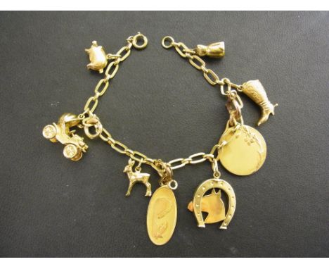 A fancy-link bracelet suspending eight assorted charms - Most with marks indicating 18ct gold - Length 19cms - Weight approx 