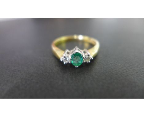 An 18 ct gold emerald and diamond three stone ring - the oval emerald measures approx. 6 mm in length - the two diamonds set 