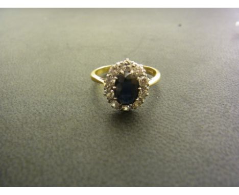 An 18 ct gold sapphire and diamond cluster ring - the sapphire measuring approx. 0.75 carats - surround by 10 round cut diamo