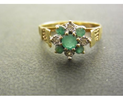 A 9ct gold emerald and diamond cluster ring  - To the textured shoulders and plain half-band - Hallmarked London - Ring size 