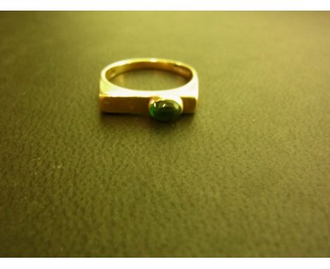 A 9ct gold emerald ring - Of angular design, the oval emerald cabochon to the bar surmount and plain band - Hallmarked London