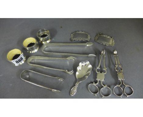 Two pairs of silver scissor action sugar nips, three pairs of silver sugar tongs, two unmarked spirit labels, a silver caddy 